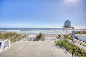 A basketball court with a net, adjacent to a beach with ocean views.