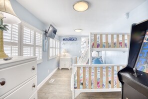 A room with a crib, a television mounted on the wall, and a dresser with drawers. - 52 Week High (North Myrtle Beach)