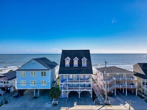 A coastal building with a balcony, a covered porch, and a view of the ocean.