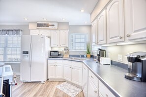 A modern kitchen with white cabinetry, a built-in microwave, a coffee maker, and a toaster. - Waterfront Retreat w/ Private Pool in Cherry Grove (North Myrtle Beach)