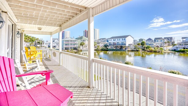 A covered deck with a view of a lake and buildings. - 5 O'Clock Poolside (North Myrtle Beach)
