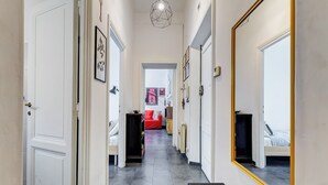 A hallway with a mirrored wall, a red sofa, and a bed in the background. - Termini Sweet Home (Rome)
