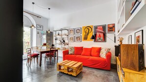 A modern living room with a red sofa, wooden coffee table, and a dining area with chairs and a table. - Termini Sweet Home (Rome)
