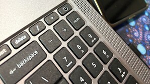 Ein Laptop mit Tastatur und ein Smartphone auf einer Glasplatte.