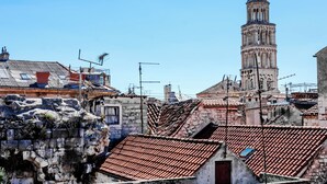 Μια ιστορική πόλη με έναν επιβλητικό πύργο, κτίρια από πέτρα και κεραμοσκεπές.