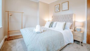 A bedroom with a bed, bedside tables, a wardrobe, and a window. - Stay Harrogate 3 Bed Holiday Home | Walk to Convention Centre | Parking (North Yorkshire)