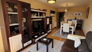 A living room with a sofa, coffee table, TV, and wooden cabinet. - Centrally located apartment in Sarria (Sarria)