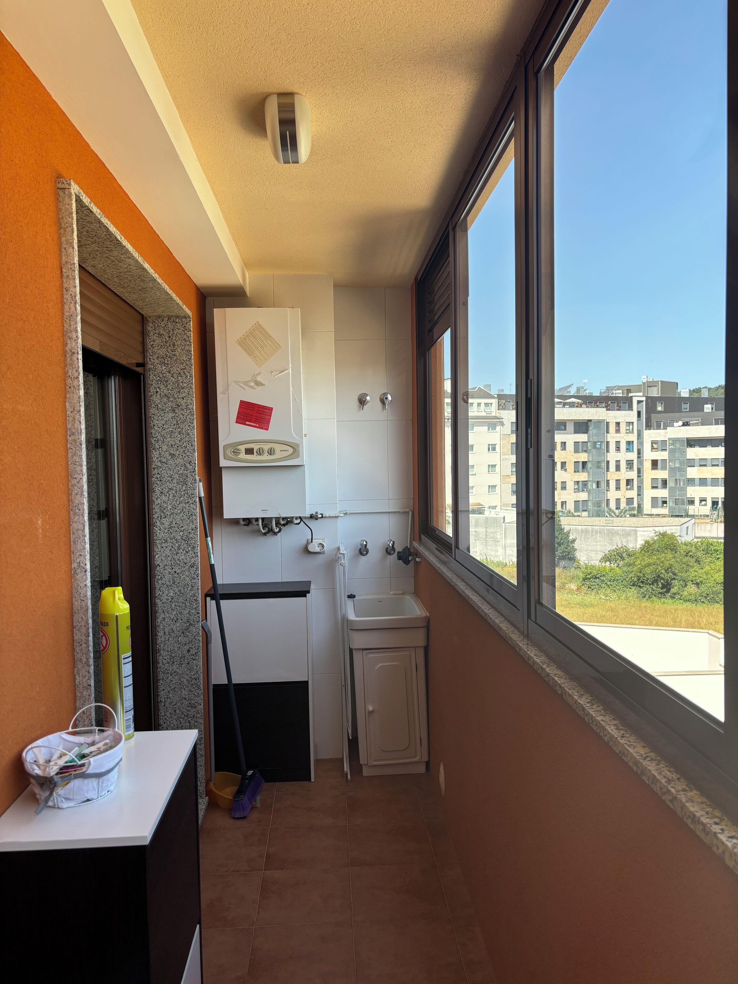 Cuina petita i senzilla amb finestra, aigüera i vista a edificis.