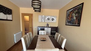 A dining area with a long table, six chairs, a central light fixture, and artwork on the walls. - Centrally located apartment in Sarria (Sarria)