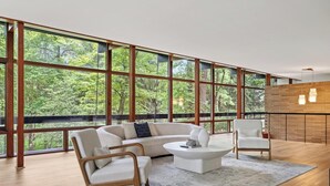 A spacious room with large windows, a white sofa, two chairs, and a coffee table.