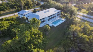 Une grande maison moderne dotée d’une piscine, entourée d’une végétation luxuriante et d’une pelouse bien entretenue.