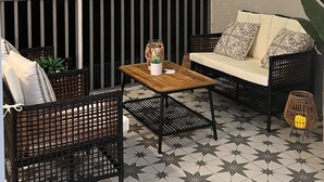 Un balcon avec un canapé, des chaises, une table et des guirlandes lumineuses.