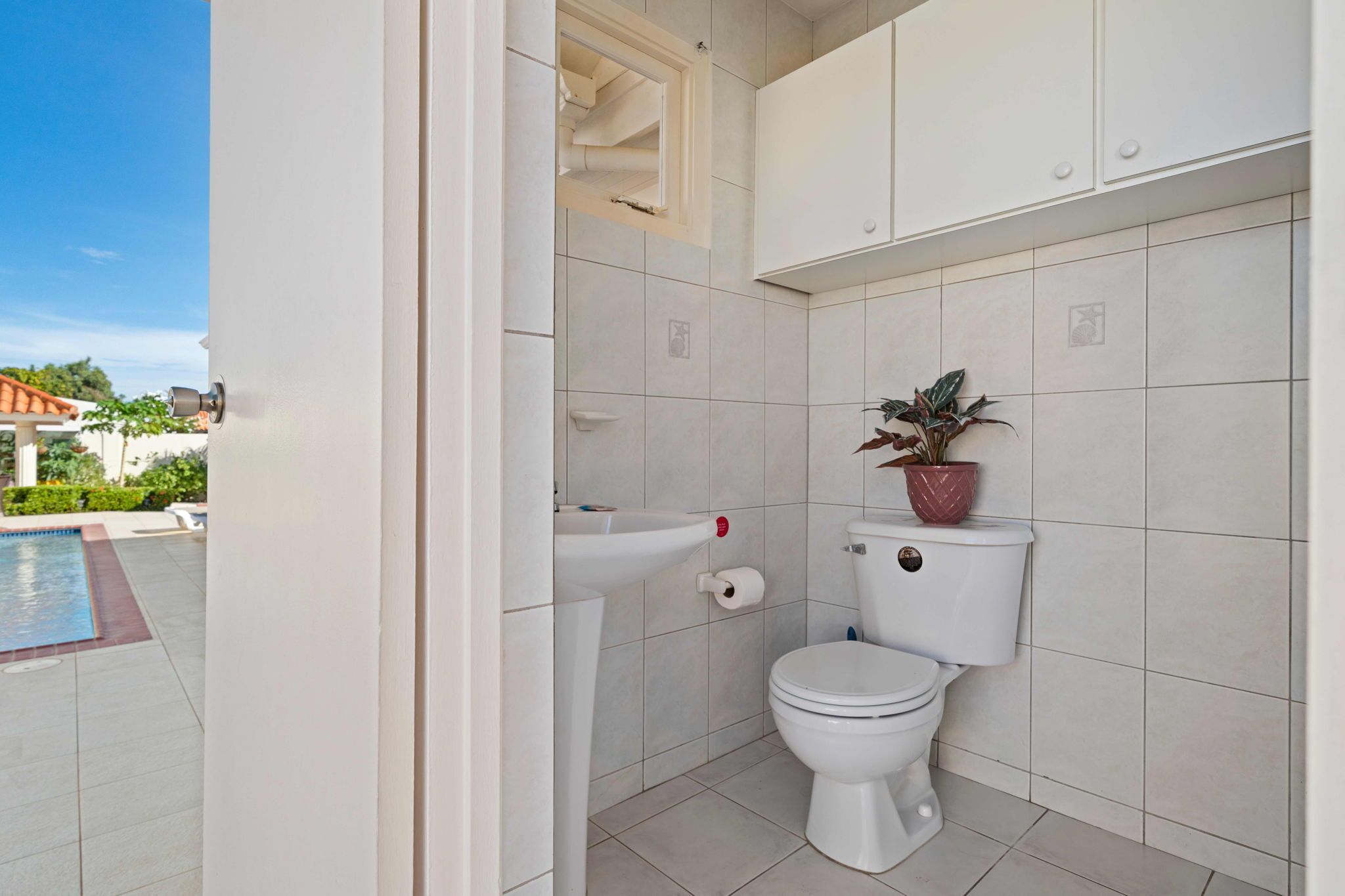 Un baño con inodoro, lavamanos y una planta en maceta.