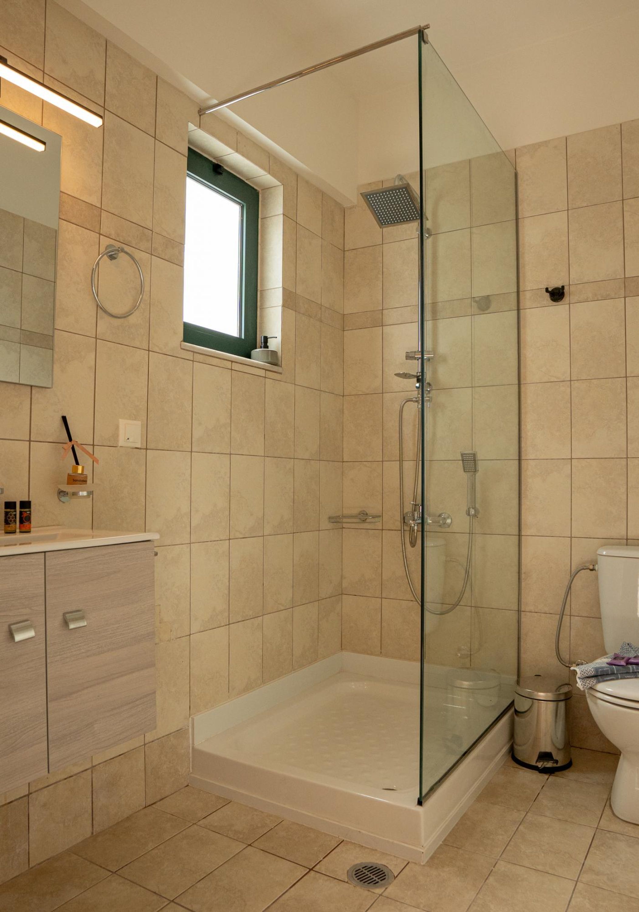 A modern bathroom with a glass-enclosed shower, a toilet, and a vanity with drawers.