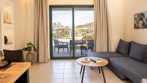 A modern living room with a sofa, a dining table, and a view of an outdoor patio area.