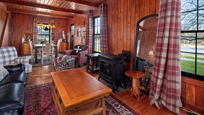 A cozy cabin interior with wooden walls, a fireplace, a sofa, a coffee table, and a dining area. - NEW LISTING!! Charming home in STOWE VILLAGE steps to Trails, Dining & Adventure (Stowe)