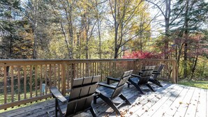 A wooden deck with Adirondack chairs, surrounded by trees with autumn foliage. - NEW LISTING!! Charming home in STOWE VILLAGE steps to Trails, Dining & Adventure (Stowe)
