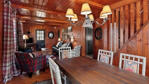 A wooden interior with a dining table, plaid furniture, and wall-mounted lamps. - NEW LISTING!! Charming home in STOWE VILLAGE steps to Trails, Dining & Adventure (Stowe)