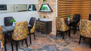 A dining area with a black and gold cabinet, a white sink, and chairs with colorful upholstery. - THE BLEVICK SUITES AND APARTMENTS (Abuja)