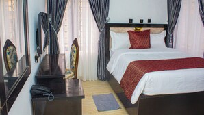 A hotel room with a bed, a desk with a telephone, and a mirror. - THE BLEVICK SUITES AND APARTMENTS (Abuja)