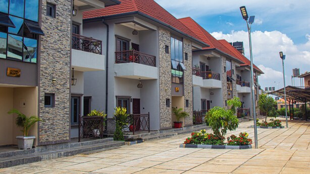 A multi-story hotel with balconies, stone facade, and red roof. - THE BLEVICK SUITES AND APARTMENTS (Abuja)