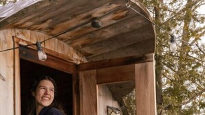 Una cabaña de madera con puerta, ventana y una lámpara.
