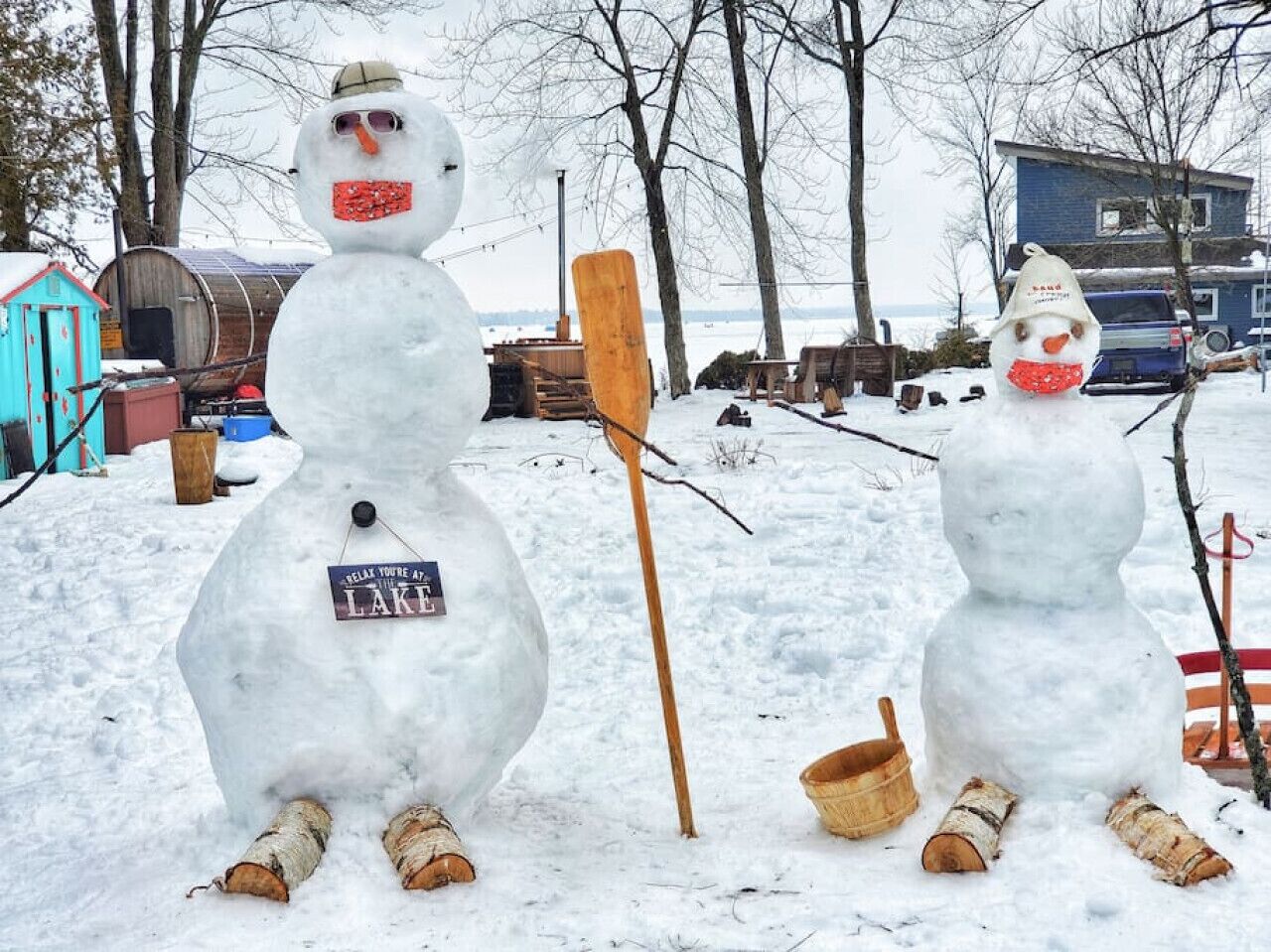 Two snowmen in a snowy outdoor setting with a sign that reads "Relax You're At Lake."
