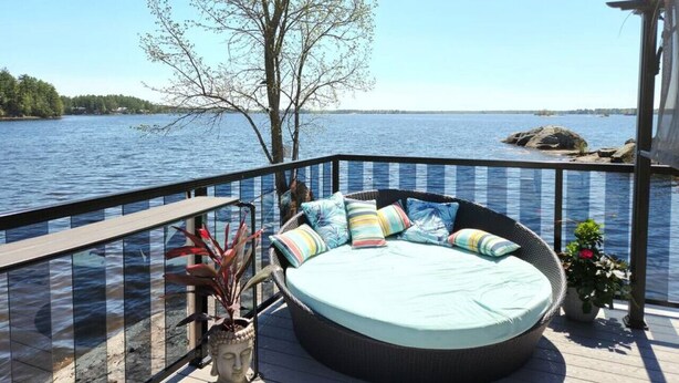 Una terraza con un espacio de estar circular, barandilla y vista a un cuerpo de agua.