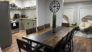 Una cocina moderna con comedor, que presenta una mesa de madera, sillas y un reloj grande en la pared.