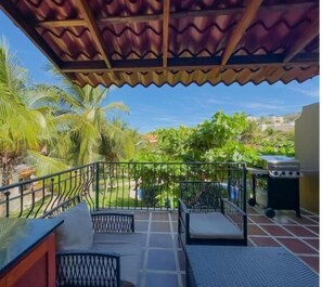 Ein überdachter Außenbereich mit Terrasse, Sitzgelegenheiten und Grill.
