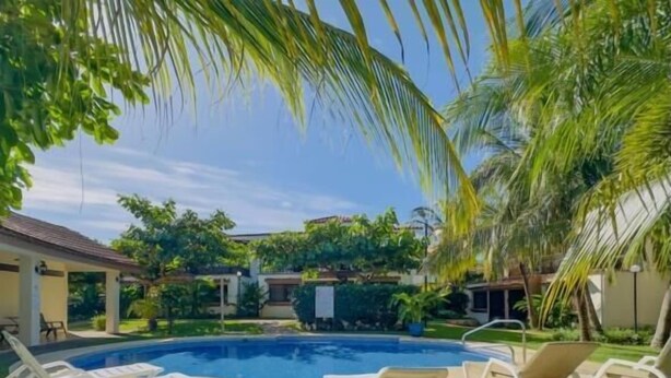 A swimming pool with lounge chairs and a covered patio area. - Jade A13 - Tropical Two-Story Retreat with Pool Views (City Playas del Coco)
