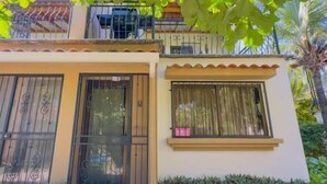A two-story building with a balcony, a door with a metal gate, and a window with curtains. - Jade A13 - Tropical Two-Story Retreat with Pool Views (City Playas del Coco)