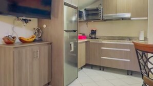 A kitchen with a refrigerator, microwave, and a TV mounted on the wall. - Jade A13 - Tropical Two-Story Retreat with Pool Views (City Playas del Coco)
