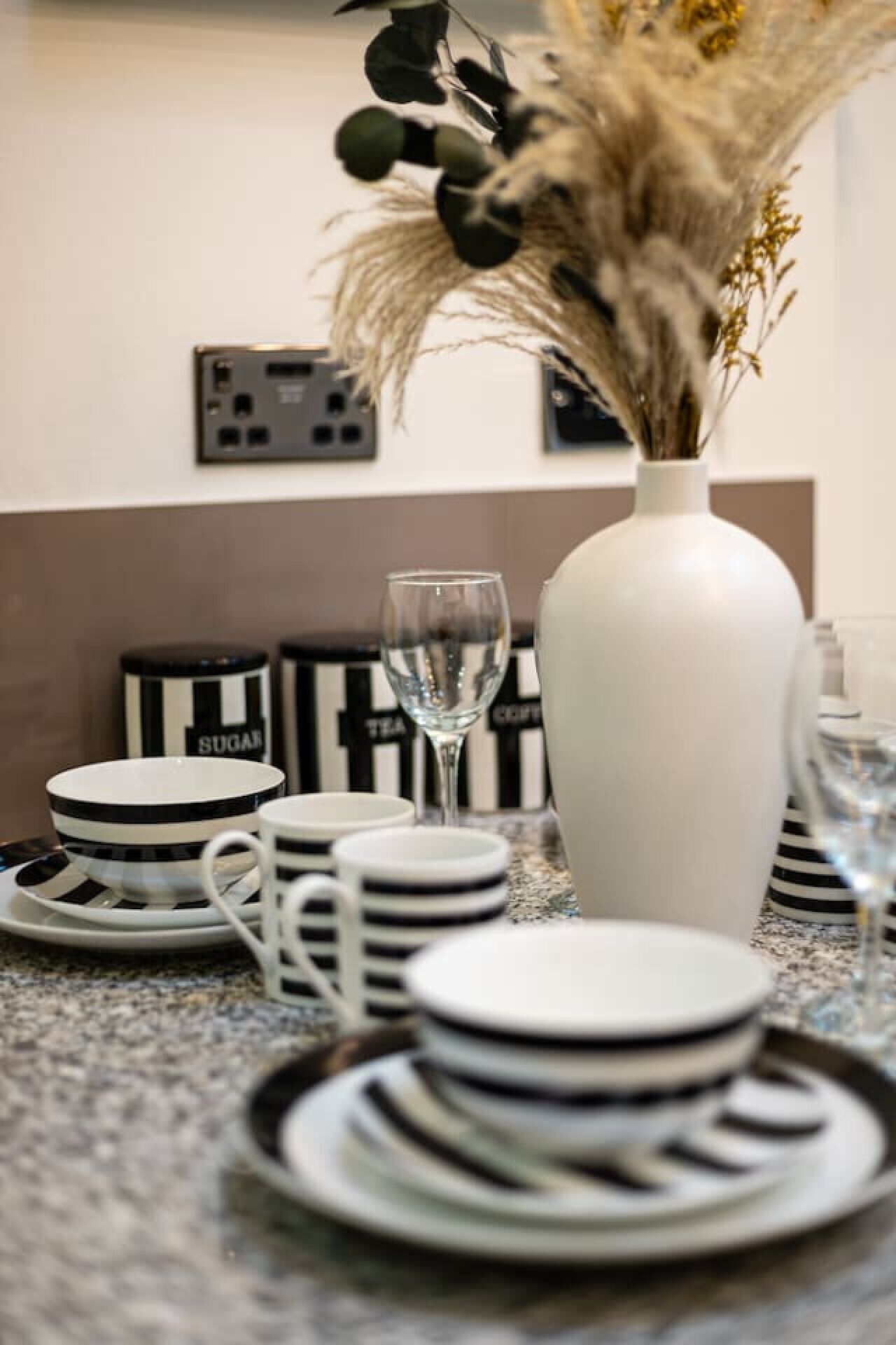 A kitchen counter with stacked plates, bowls, and a glass of water.