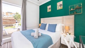 Quarto de hotel com cama, duas mesas de cabeceira, janela com cortinas e vista para o exterior.