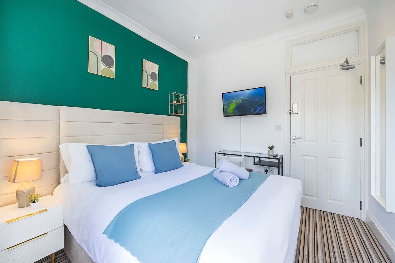 Een hotelkamer met een groot bed, een bureau, een televisie en een deur.