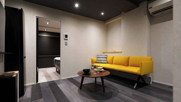 A modern living room with a yellow sofa, a round coffee table, and a grey patterned floor. - Real Life Iidabashi chic 1-bedroom midtown 3P (Tokyo)
