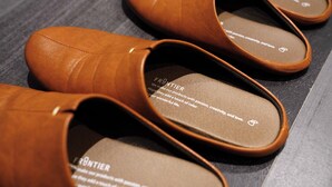 A pair of brown leather slippers with a visible brand name and a slogan on the insole. - Real Life Iidabashi chic 1-bedroom midtown 3P (Tokyo)
