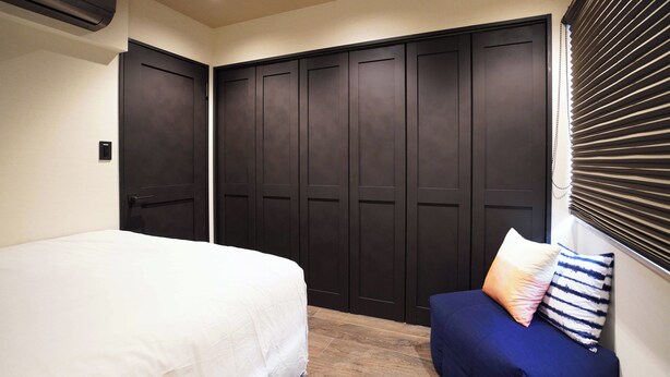 A bedroom with a bed, a sofa, and a wardrobe.
