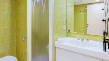 Ein Badezimmer mit gelben Fliesen, einem weißen Waschbecken und einem Spiegel.
