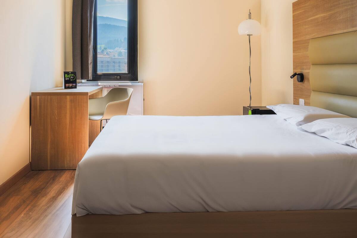Ein Hotelzimmer mit Bett, Schreibtisch, Stuhl und Lampe.