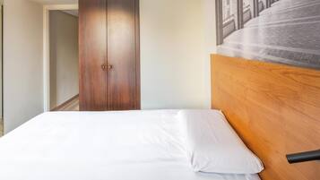 A hotel room with a wooden headboard, a white bed, and a wardrobe.