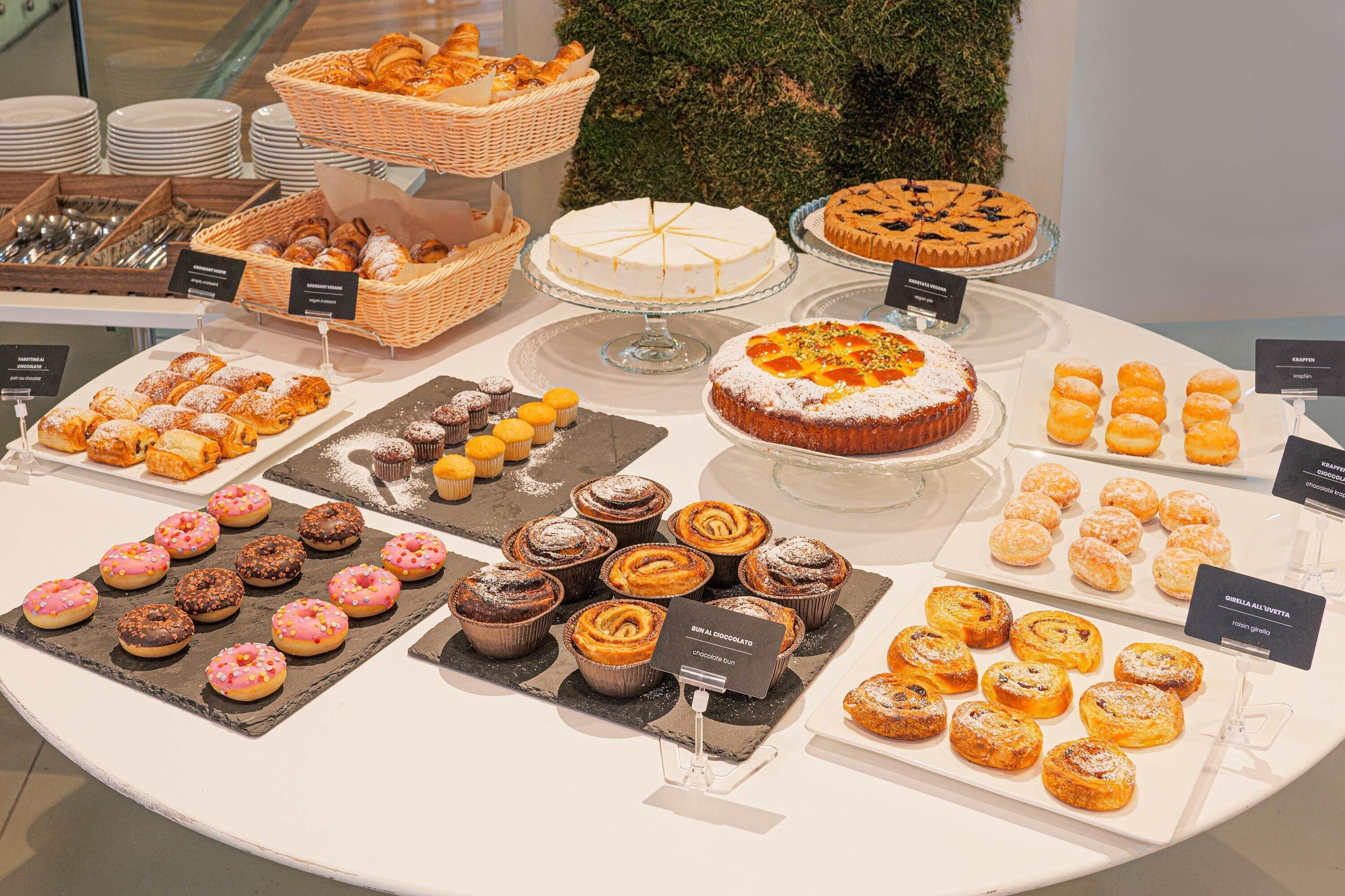 Ein Buffet mit verschiedenen Backwaren, darunter Gebäck, Kuchen und Donuts.