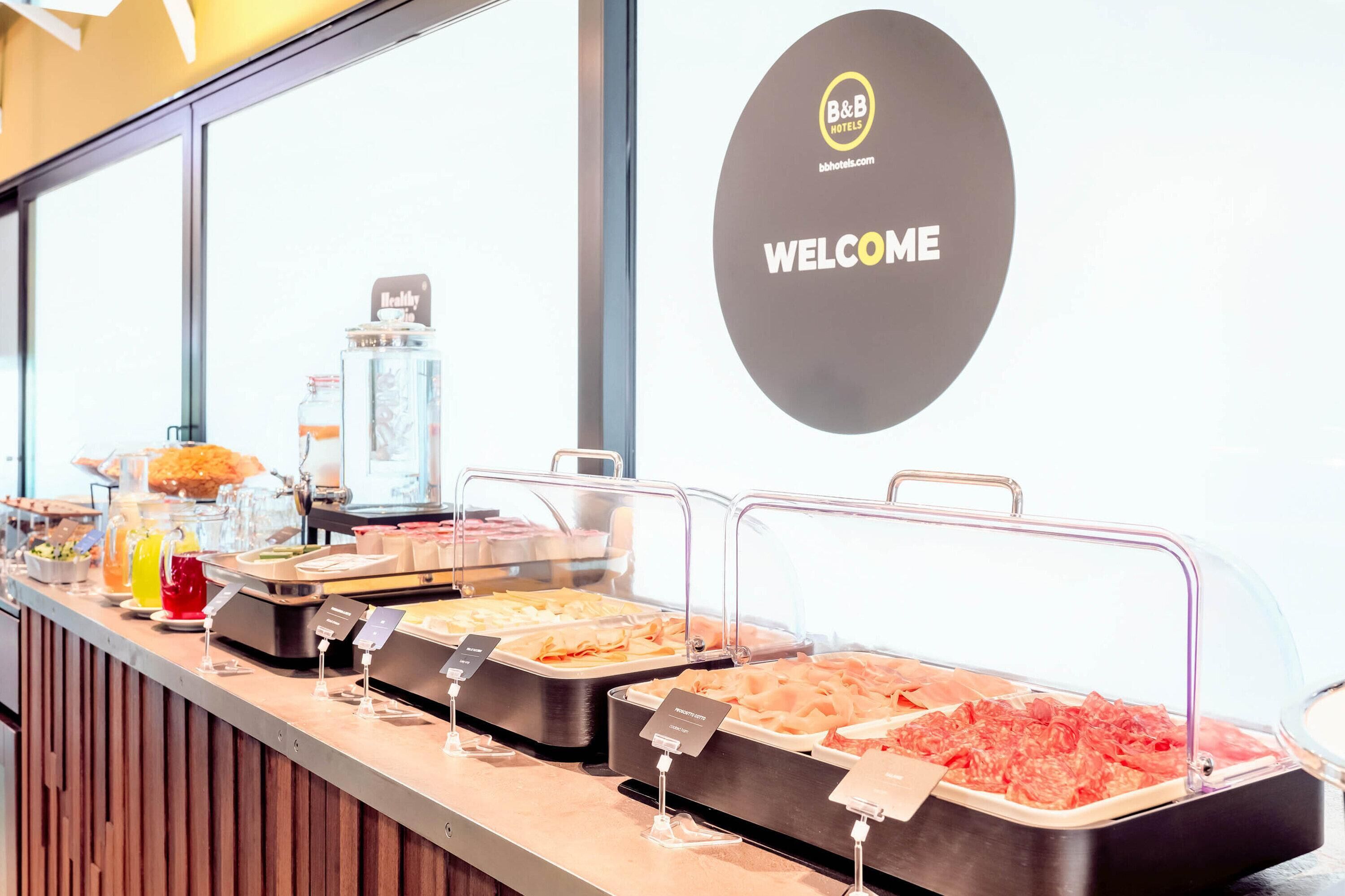 Un comptoir de buffet proposant divers plats, un panneau d’accueil et un panneau d’information sur les règles d’hygiène.