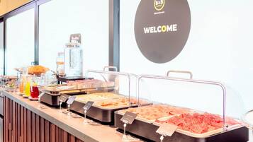Un comptoir de buffet proposant divers plats, un panneau d’accueil et un panneau d’information sur les règles d’hygiène.