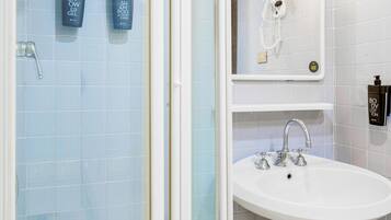 Un baño con ducha, lavamanos y dos botellas de gel de ducha en la pared.