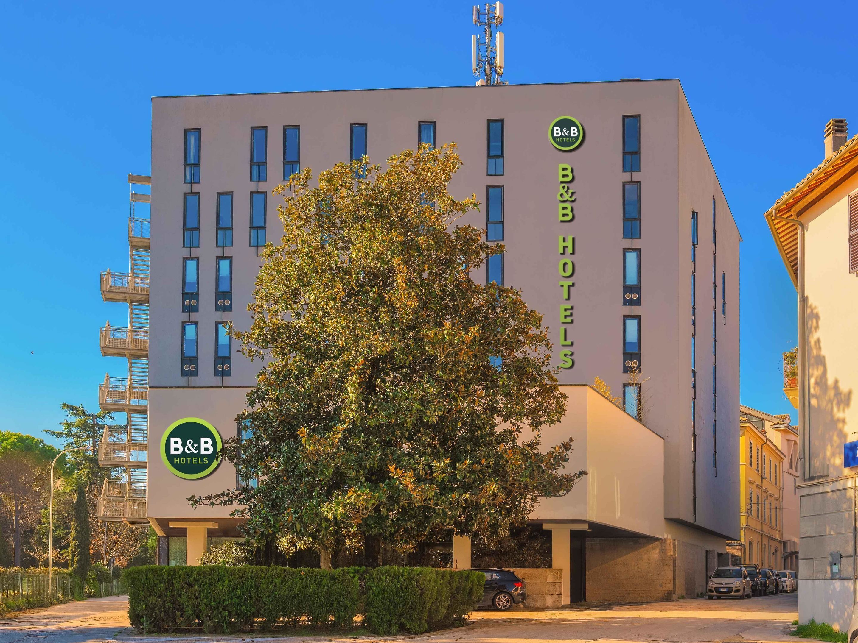Ein Bed and Breakfast Hotel mit moderner Fassade, zahlreichen Fenstern und einem großen Baum davor.