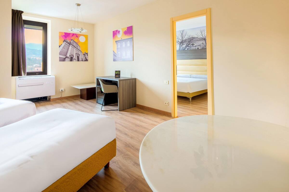 Ein Hotelzimmer mit zwei Betten, einem Schreibtisch, einem Stuhl und einem Tisch.