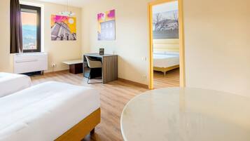 Habitación de hotel con dos camas, un escritorio, una silla y una mesa.