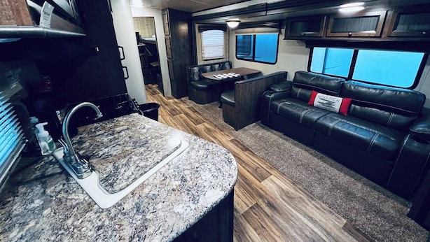 A compact RV interior with a kitchen area, a seating area with a couch, and a small dining table. - Secluded Lakeside RV Experience (Bridgeport)